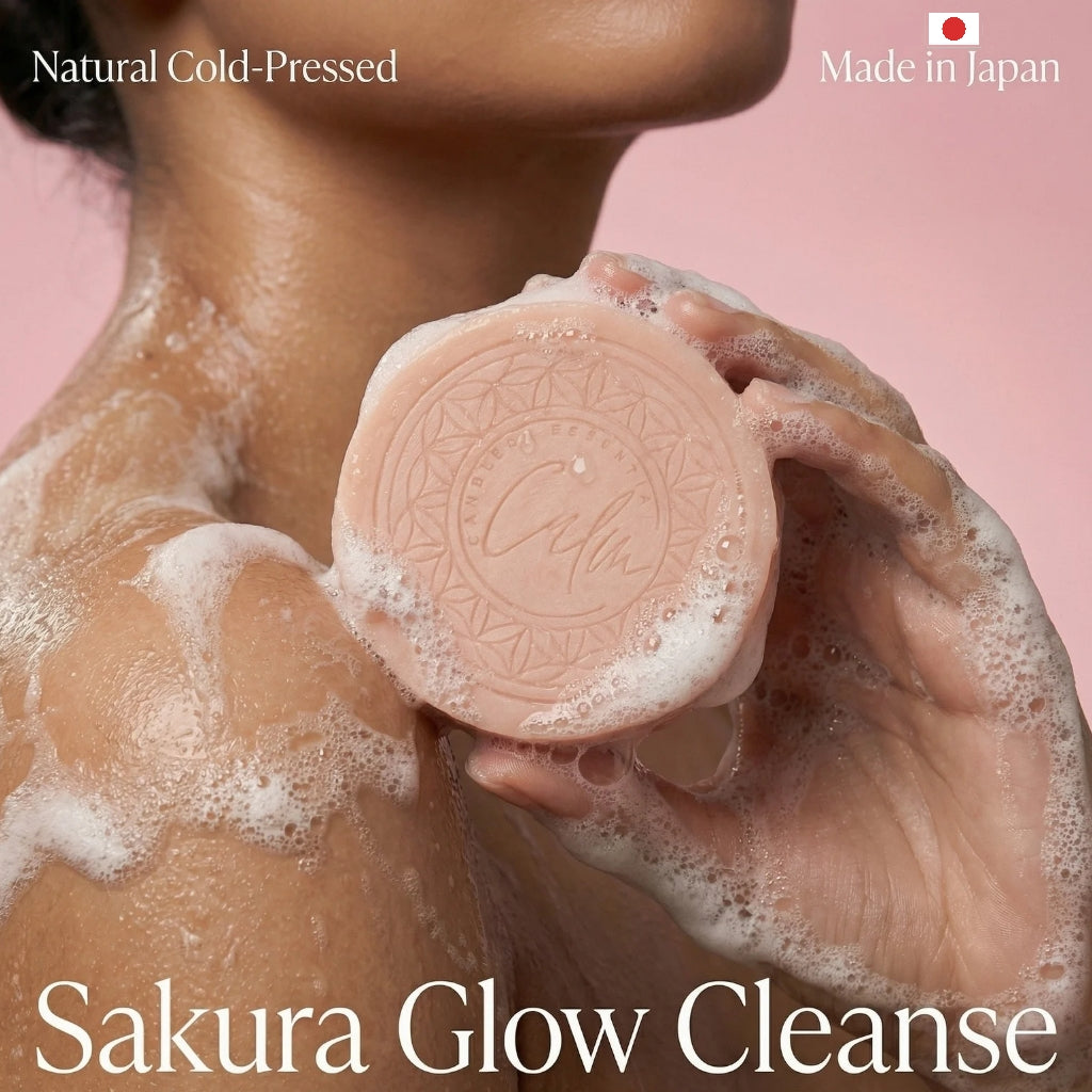 Person holding a soaped bar with 'Sakura Glow Cleanse' branding against a pink background.